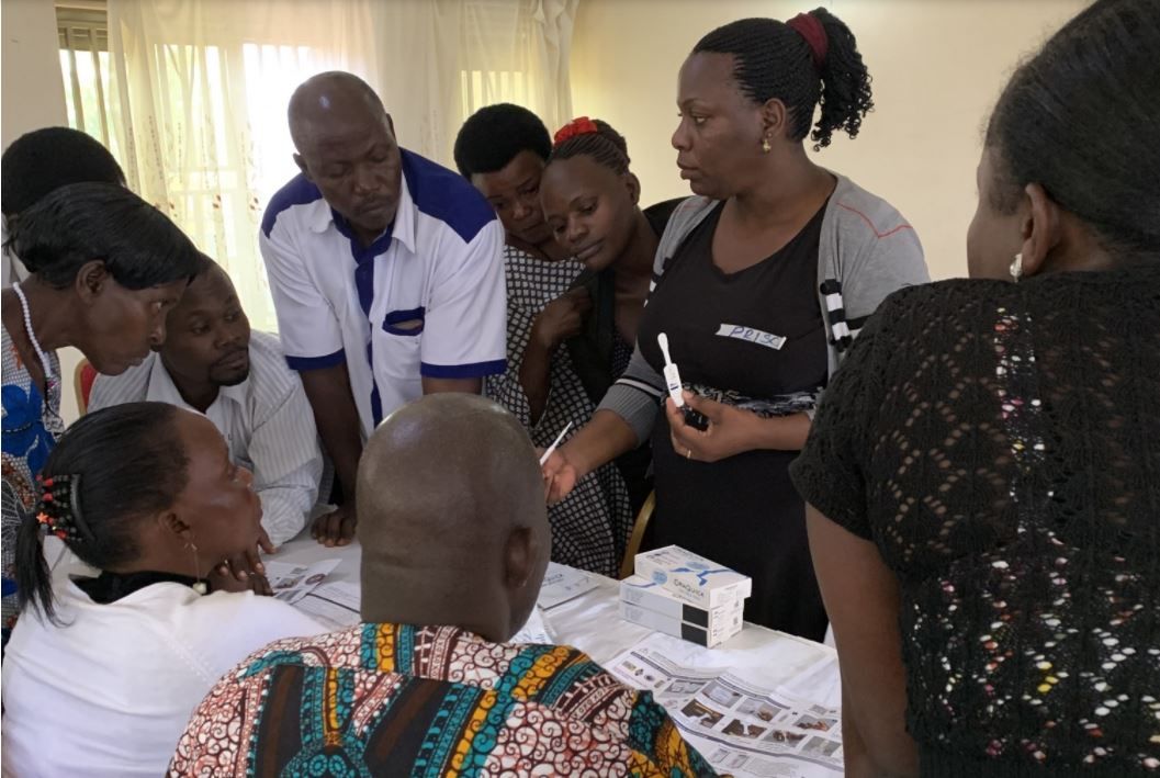 Ms. Prisca Asiimwe, a nurse from Mbarara Regional Referral Hospital (second from right), provides instruction on use of oral swab rapid HIV tests to traditional healers in the intervention arm of the trial.